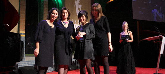 2011 Vier Frauen in eleganten schwarzen Kleidern stehen auf einer Bühne, während eine weitere Frau im Hintergrund moderiert.