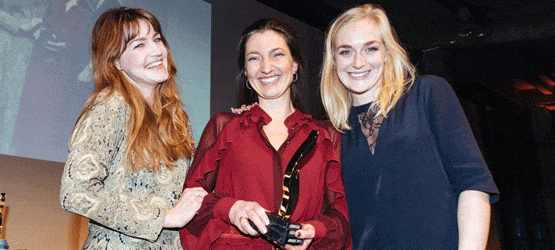 EEA_2017 Drei Frauen lächeln und posieren zusammen, eine hält einen Preis in der Hand, im Hintergrund eine festliche Veranstaltung.