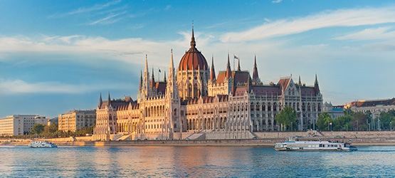 budapest-GettyImages-119356132 Panoramaansicht des ungarischen Parlamentsgebäudes in Budapest am Ufer der Donau bei Sonnenuntergang.