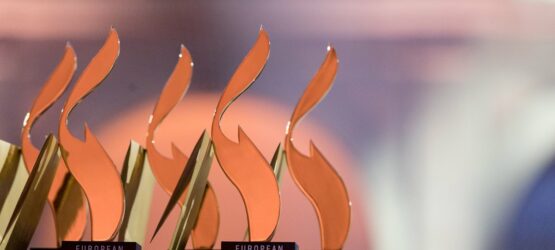 2019-12-29-european-excellence-awards-show-188 Mehrere Auszeichnungen mit orangefarbenen Flammen auf schwarzem Sockel, beschriftet mit "EUROPEAN EXCELLENCE".