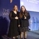 Zwei Frauen stehen auf einer Bühne bei den European Excellence Awards 2024, eine hält einen Preis in der Hand.