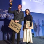 Zwei Personen auf einer Bühne halten Schilder mit den Aufschriften "FASHION Yes! FASCISM No!" und "FASCHISMUS DOCH SEHEN!