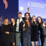 Sechs Personen feiern auf der Bühne mit einem Preis bei den European Excellence Awards 2024.