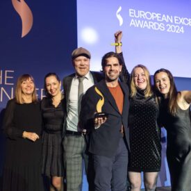 Sechs Personen feiern auf der Bühne mit einem Preis bei den European Excellence Awards 2024.
