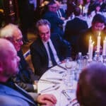 Elegante Award-Show mit Gästen an festlich gedeckten Tischen und Kerzenlicht in einem stilvollen Ambiente.