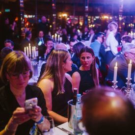 Menschen in eleganter Kleidung sitzen an festlich gedeckten Tischen bei der European Excellence Awards 2025.