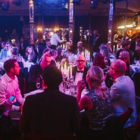 Elegante Award-Show mit Gästen an Tischen, Kerzenlicht und festlicher Atmosphäre in einem stilvollen Veranstaltungsort.