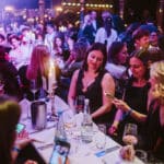 Elegante Award-Show mit Gästen in formeller Kleidung, Kerzenlicht und festlicher Atmosphäre.