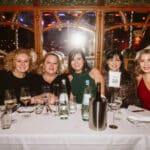 Fünf Frauen in eleganter Kleidung sitzen an einem Tisch bei der European Excellence Awards Veranstaltung.